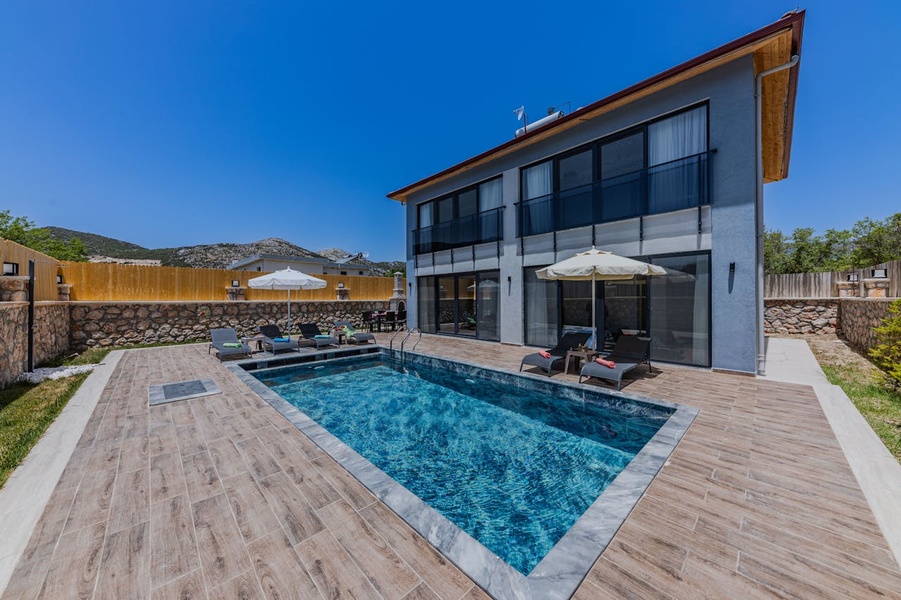 A contemporary villa with a swimming pool and patio area, perfect for summer vacations.